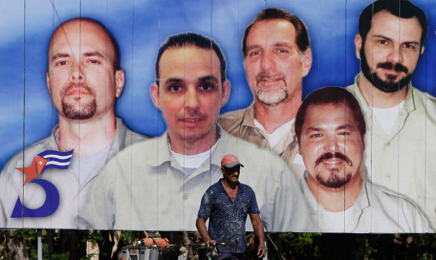 A man walks past in front a billboard with images of five Cuban intelligence agents imprisoned in U...