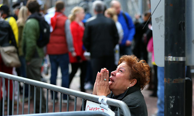 A woman kneels and prays at the scene of the first explosion on Boylston Street near the finish lin...
