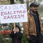 
              Savelle Velazquez, 6, holds a sign accompanied by his stepfather, Isaiah, as they wait outside to attend a rally for Democratic presidential candidate Bernie Sanders, I-Vt., at Hudson's Bay High School in Vancouver, Wash., Sunday, March 21, 2016. (Natalie Behring/The Columbian via AP)
            