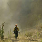 
 A firefighter walks away from a smoke-filled hillside while fighting the First Creek Fire, Tuesday, Aug. 18, 2015, near Chelan, Wash. Wildfires are putting such a strain on the nation's firefighting resources that authorities have activated the military and sought international help to beat back scores of blazes burning uncontrolled throughout the dry West. (AP Photo/Ted S. Warren)
            