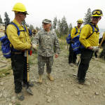 Major General Bret Daugherty, second from left, commander of Washington Army and Air National Guard forces, greets Washington National guard soldiers who were fighting the First Creek Fire above lake Chelan Tuesday, Aug. 18, 2015, near Chelan, Wash. Under Daugherty's direction, guard troops have undergone "Red Card" and other fire fighting training in order to be able to help fight wildfires in the state. (AP Photo/Ted S. Warren)