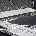 Workers driving small tractors, right, plow snow off a tarp covering the field at MetLife Stadium as a tent protects the end zone area ahead of Super Bowl XLVIII as crews removed snow following a snow storm, Wednesday, Jan. 22, 2014, in East Rutherford, N.J. Super Bowl XLVIII, which will be played between the Denver Broncos and the Seattle Seahawks on Feb. 2, will be the first NFL title game held outdoors in a city where it snows. (AP Photo/Julio Cortez)