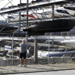 A passerby takes a photo, Friday, July 5, 2013 of some of the 14 boats that were damaged in a late-night fire Thursday at the Lake Union Skylaunch Marina. Seattle fire investigators are blaming illegal fireworks for the blaze. (AP Photo/Ted S. Warren)
