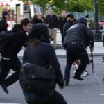 A Seattle Police officer is tripped up by a string held by protesters as he runs at them with his baton during a May Day march that began as an anti-capitalism protest and turned into demonstrators clashing with police, Wednesday, May 1, 2013, in downtown Seattle. (AP Photo/Ted S. Warren)
