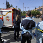 Emergency workers stand near the scene of a shooting on the campus of Seattle Pacific University Thursday, June 5, 2014, in Seattle. A lone gunman armed with a shotgun opened fire in Otto Miller Hall, hidden behind the vehicle at left, on the campus, killing one person before he was subdued by a student as he tried to reload, police said. Police say the student building monitor at Seattle Pacific University disarmed the gunman and several other students held him until police arrived at the Otto Miller building. (AP Photo/Elaine Thompson)