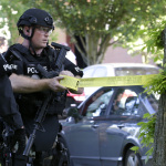 A Seattle Police SWAT team officer strings police tape at the scene of a shooting, Thursday, June 5, 2014, at Seattle Pacific University in Seattle. (AP Photo/Ted S. Warren)