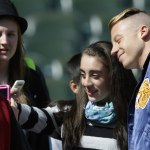 Rapper Macklemore, right, joins in a "selfie" photo Thursday, April 10, 2014 with one of a group of Seattle-area students filming an anti-bullying video at Safeco Field in Seattle. (AP Photo/Ted S. Warren)