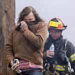 A worker from a nearby business covers his face from thick smoke as he is escorted by a firefighter away from a building on fire Tuesday, Sept. 30, 2014, in Seattle's Fremont neighborhood. No injuries were reported from the fire, which sent flames bursting through the roof of the building and created a large plume of smoke visible from downtown. (AP Photo/Elaine Thompson)