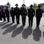 Firefighters stand at attention as a motorcade passes before a memorial service for three firefighters killed in a wildfire, Sunday, Aug. 30, 2015, in Wenatchee, Wash. Firefighters Richard Wheeler, Andrew Zajac and Thomas Zbyszewski died Aug. 19 in a fire near Twisp, Wash. (AP Photo/Elaine Thompson)