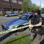 A Seattle Police SWAT team officer strings police tape at the scene of a shooting Thursday, June 5, 2014 at Seattle Pacific University in Seattle. (AP Photo/Ted S. Warren)