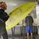 After voting, Mike Weigart, 30, carries his ballot and his surfboard to the ballot box at the polling place at the Venice Beach lifeguard headquarters in Los Angeles Tuesday, Nov. 6, 2012. Weigart said "It's awesome the polling place is where I surf." (AP Photo/Reed Saxon)