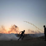 Palestinian protesters run for cover from tear gas fired by Israeli soldiers during clashes on the Israeli border with Gaza in Buriej, central Gaza Strip on Thursday. (AP Photo/Khalil Hamra)