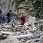 Searchers slowly move through a field of debris following a deadly mudslide, Tuesday, March 25, 2014, in Oso, Wash. (AP Photo/Elaine Thompson)