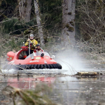 Searchers work from aboard a hovercraft while looking through debris from a mudslide, Tuesday, March 25, 2014, in Oso, Wash. (AP Photo/Elaine Thompson)