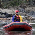 A searcher paddles a boat through a debris field following a deadly mudslide, Tuesday, March 25, 2014, in Oso, Wash. (AP Photo/Elaine Thompson)