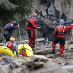 Searchers in boats and on foot look through debris following a deadly mudslide Tuesday, March 25, 2014, in Oso, Wash. (AP Photo/Elaine Thompson)