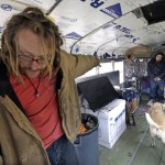 Danny Fletcher, left, calls to his dogs as Joshua Madrid looks on in an old bus they share with three dogs in a temporary city-approved parking area for people living in their vehicles in Seattle. Fletcher, 32, who sleeps in his car at night, prefers the quiet of the parking zone to the harassment he faced in other parts of the city. "We just want a safe place. Give us a safe place to park where neighbors won't harass us," he said. "We're homeless. We're not diseased." (AP Photo/Elaine Thompson)