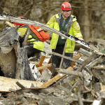 A search and rescue worker clears debris from a house Tuesday, March 25, 2014, on the western edge of the massive mudslide that struck near Arlington, Wash., on Saturday, killing at least 14 people and leaving dozens missing. (AP Photo/Ted S. Warren, Pool)