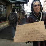 Billy Meyer, who said he has been homeless in both Portland, Ore., and Seattle in the past year, holds a cardboard sign asking for help near a pedestrian bridge leading to the ferry dock in downtown Seattle on Tuesday, Feb. 9, 2016. (AP Photo/Ted S. Warren)