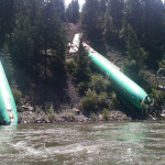 This Sunday, July 6, 2014 photo by Jerry Compton provided by Wiley E. Waters Whitewater Rafting shows a freight train that derailed near Alberton in western Montana, sending three cars carrying aircraft components down a steep embankment and into the Clark Fork River on Thursday, July 3. Removing three Boeing 737 fuselages could take until Tuesday. Montana Rail Link spokeswoman Lynda Frost said a crew of 50 with eight heavy equipment machines is working in conjunction on the steep bank. (AP Photo/Wiley E. Waters Whitewater Rafting, Jerry Compton)