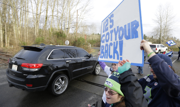 Fans hold a sign that reads “12’s Got Your Back,” as Seattle Seahawks players, co...