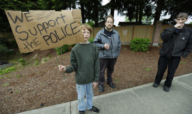 Matteo Johnston, 13, left, holds a sign that reads “Don’t steal beer! We support the po...