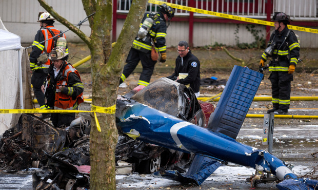 Investigators and emergency personnel look over the aftermath of a news helicopter crash Tuesday, M...