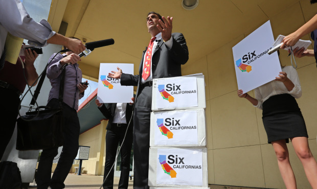 Silicon Valley venture capitalist Tim Draper talks to reporters next to six boxes of petitions for ...