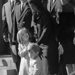FILE - In this Monday, Nov. 25, 1963 file photo, Caroline Kennedy, 5, looks to her mother, Jacqueline Kennedy, as she clutches her hand, accompanied by John F. Kennedy, Jr., 3, while leaving St. Matthew's Cathedral after the funeral Mass for President John F. Kennedy in Washington. It is his third birthday; his sister will turn 6 two days later. Behind them are Robert P. Fitzgerald, first cousin of the president, Rose Kennedy, mother of the president, and Robert F. Kennedy, his brother, far right. Men at left are unidentified. (AP Photo/William C. Allen, File)